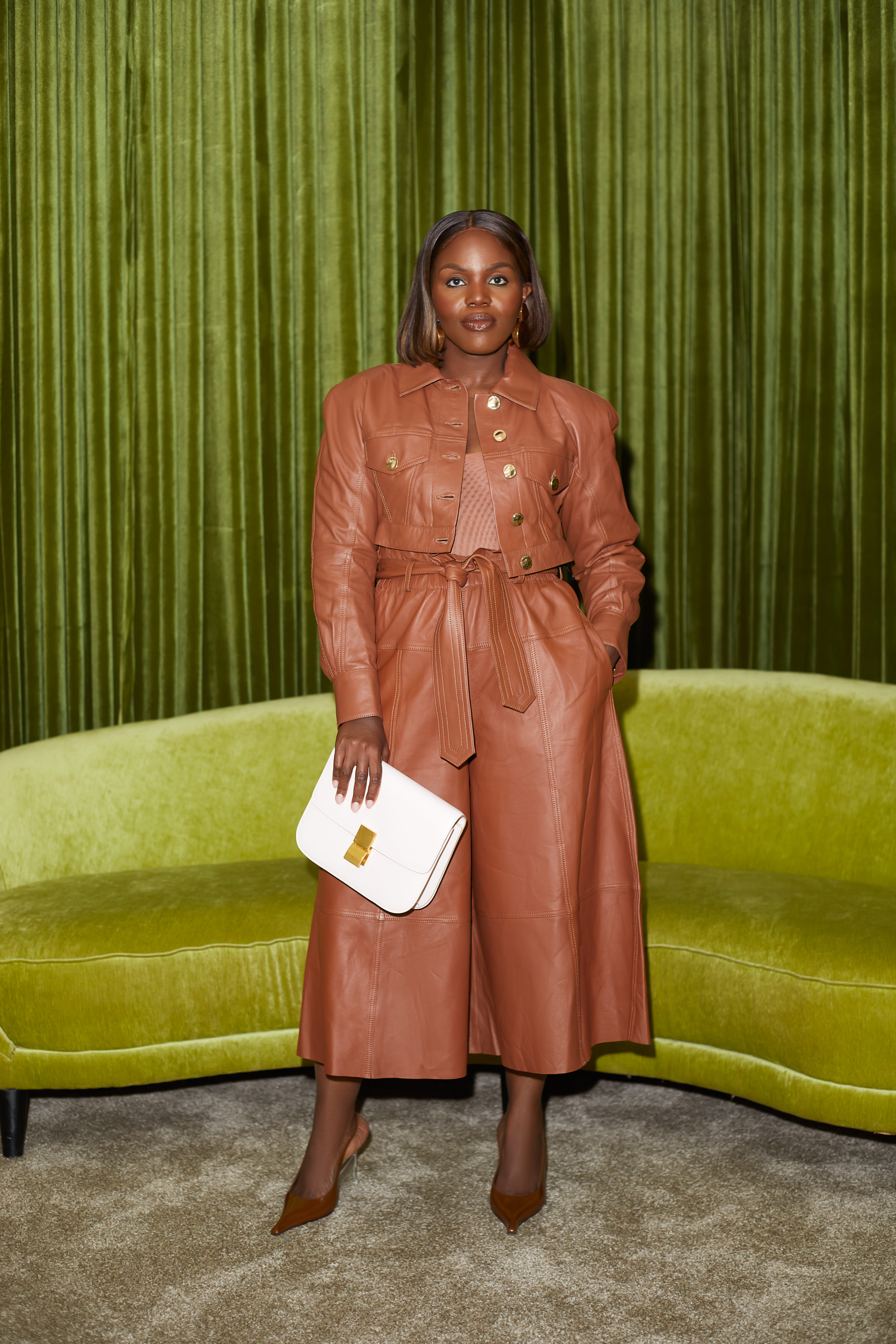 Sacha Okoh in a terracotta leather outfit with a white handbag